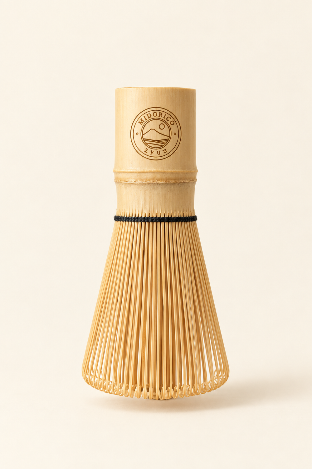 Engraved 100-prong bamboo matcha whisk standing upright on a warm cream background